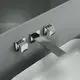 Wand-Waschtischarmatur mit zwei quadratischen Bedienelementen und einem langen Auslauf, montiert an einer glatten Oberfläche. Ideal Standard Produkt in silberner Ausführung.